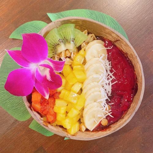 a bowl of fruit with a flower on a table at ALOHADAYS Nishijin Guesthouse in Kyoto