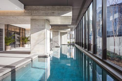 a swimming pool in a building with glass windows at Urban Rest Southbank in Melbourne