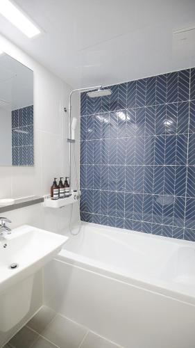 a bathroom with a tub and a sink and a mirror at WECO STAY Myeongdong in Seoul