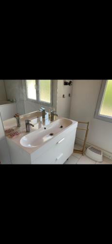 une salle de bain blanche avec un lavabo et une fenêtre dans l'établissement Maison familiale à Domino, à Saint-Georges-dʼOléron