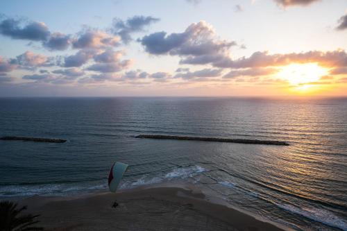 a person on a beach with a kite in the ocean at Panoramic Sea View Luxury Suite in Netanya