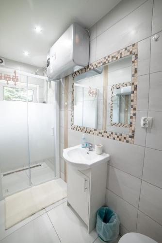 a white bathroom with a sink and a shower at Myśliwski in Jagodne Wielkie