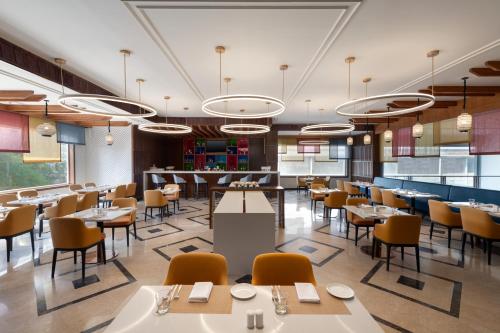 a rendering of a restaurant with tables and chairs at Ramada Encore by Wyndham Udaipur Roopnagar in Udaipur