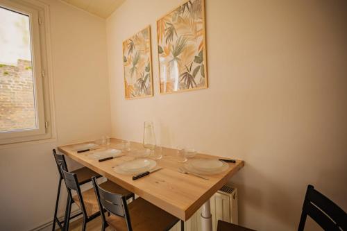 - une table à manger avec des chaises et des assiettes dans l'établissement Le Nid Secret 5 Minutes a pied de la plage avec place Parking privée, au Havre