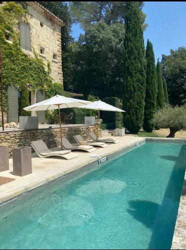 une piscine avec chaises et parasols dans l'établissement La Magnanerie d aubais, à Aubais