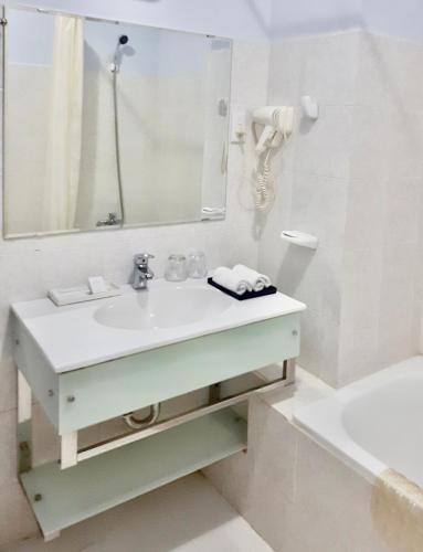 a bathroom with a sink and a mirror and a tub at Chau Pho Hotel in Chau Doc
