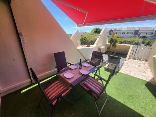 - une table et des chaises sur une terrasse avec un parasol dans l'établissement Naturistecapdagde Héliopolis avec garage Katrina, au Cap d'Agde