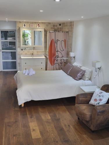 une chambre avec un grand lit blanc et un canapé dans l'établissement Naturistecapdagde Héliopolis avec garage Katrina, au Cap d'Agde