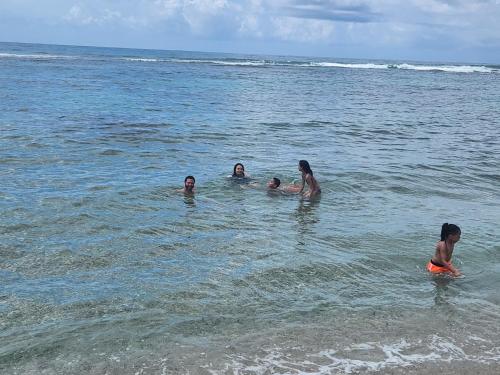 a group of people swimming in the ocean at Villa Tesoros del Mar - Luxury Beachfront Villa with Natural Pool, Jacuzzi, Mountain Views, Yoga, BBQ, Wi-Fi, Pet & Family Friendly, Barahona Adventures in El Arroyo