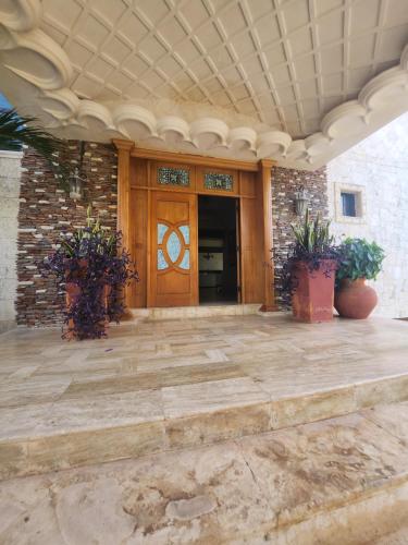 a front porch with a wooden door and potted plants at Villa Tesoros del Mar - Luxury Beachfront Villa with Natural Pool, Jacuzzi, Mountain Views, Yoga, BBQ, Wi-Fi, Pet & Family Friendly, Barahona Adventures in El Arroyo