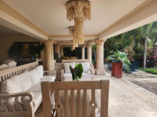 a porch with chairs and a table and a chandelier at Villa Tesoros del Mar - Luxury Beachfront Villa with Natural Pool, Jacuzzi, Mountain Views, Yoga, BBQ, Wi-Fi, Pet & Family Friendly, Barahona Adventures in El Arroyo