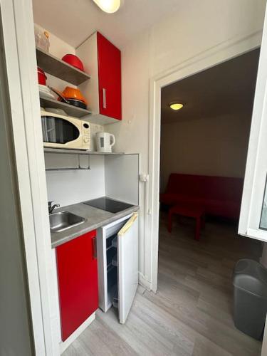 - une petite cuisine avec un évier et des placards rouges dans l'établissement Charmant studio Carmes 4 - CDDT, à La Rochelle