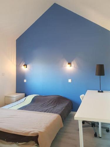 Cette chambre comprend 2 lits et un mur bleu. dans l'établissement Super appart rue des caves à vin, à Saumur