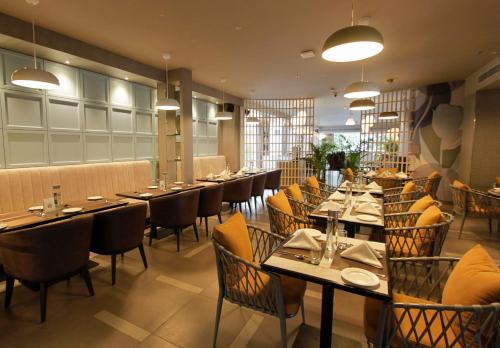 a restaurant with long tables and chairs and lights at Mercure Chandigarh Tribune Chowk in Chandīgarh
