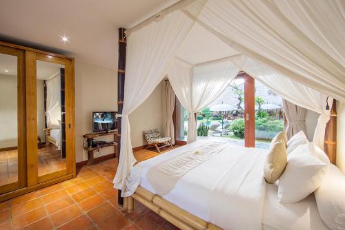 a bedroom with a large white bed with a window at Villa Omah Padi Ubud in Ubud
