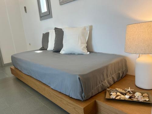 a bed with pillows and a table with a lamp at CAELI PAROS by Kostas & Joanna Studios in Logaras