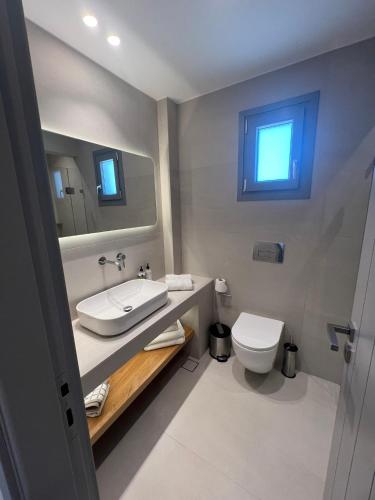 a bathroom with a sink and a toilet and a mirror at CAELI PAROS by Kostas & Joanna Studios in Logaras