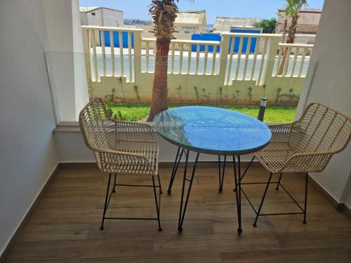 a glass table and two chairs on a balcony at Hiba's studio in Mohammedia
