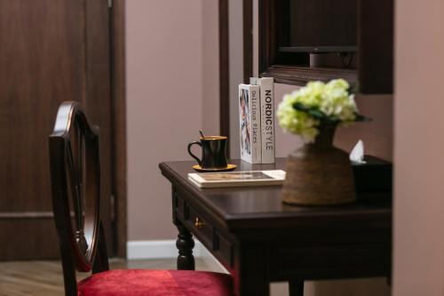 a desk with a vase of flowers and a book at Acoustic Hotel & Spa in Hanoi