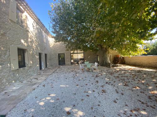 a patio with a table and chairs under a tree at La Ferme, propriété d'exception in Puygiron