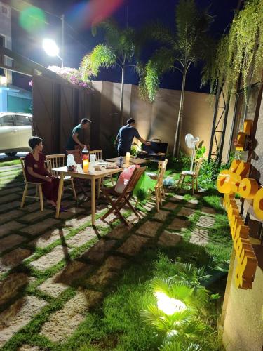 a group of people sitting at a table in a yard at Vanilla Ho Tram Homestay in Ho Tram