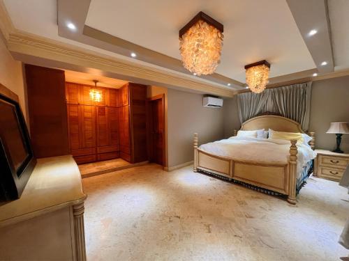 a bedroom with a bed and a television and chandeliers at Villa Tesoros del Mar - Luxury Beachfront Villa with Natural Pool, Jacuzzi, Mountain Views, Yoga, BBQ, Wi-Fi, Pet & Family Friendly, Barahona Adventures in El Arroyo