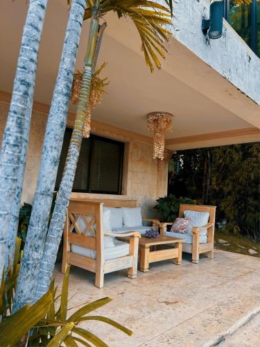 two chairs and a table on a patio with palm trees at Villa Tesoros del Mar - Luxury Beachfront Villa with Natural Pool, Jacuzzi, Mountain Views, Yoga, BBQ, Wi-Fi, Pet & Family Friendly, Barahona Adventures in El Arroyo