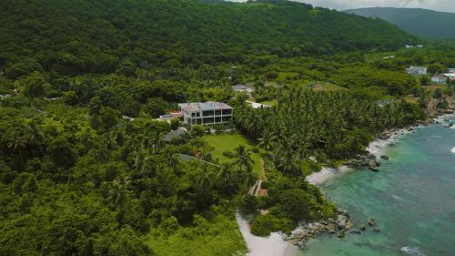an aerial view of a house on a beach at Villa Tesoros del Mar - Luxury Beachfront Villa with Natural Pool, Jacuzzi, Mountain Views, Yoga, BBQ, Wi-Fi, Pet & Family Friendly, Barahona Adventures in El Arroyo