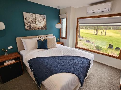 a bedroom with a large bed and a window at Tuckers Lane Boutique Accommodation in Rothbury