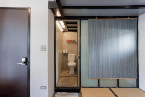 a bathroom with a toilet and a glass door at 赤樓古巷民宿 6-12人可包棟 in Tainan