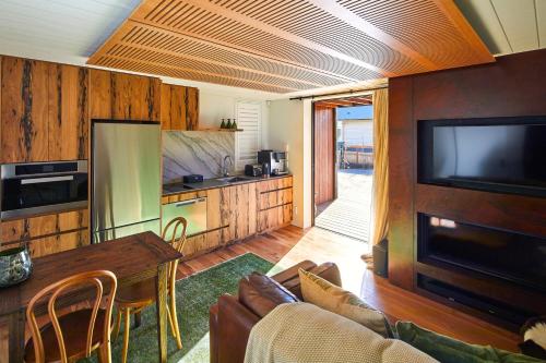 a living room with a tv and a table and a kitchen at Newton Heights in Akaroa