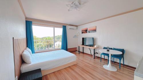 a bedroom with a bed and a table and a window at Garden in Jeju 201 in Seogwipo