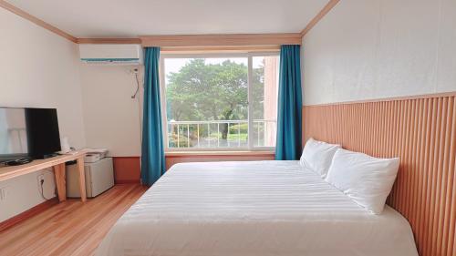 a bedroom with a large bed and a window at Garden in Jeju 201 in Seogwipo