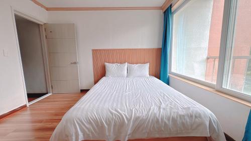 a white bed in a room with a large window at Garden in Jeju 201 in Seogwipo
