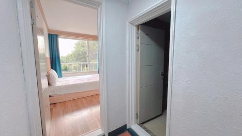 an open door to a room with a bed and a window at Garden in Jeju 201 in Seogwipo