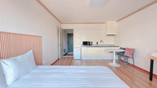 a bedroom with a white bed and a kitchen at Garden in Jeju 201 in Seogwipo