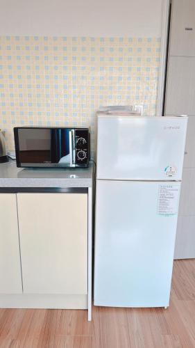 a white refrigerator next to a counter with a microwave at Garden in Jeju 201 in Seogwipo