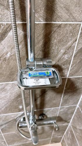 a metal toothbrush holder on a tile wall at Garden in Jeju 201 in Seogwipo