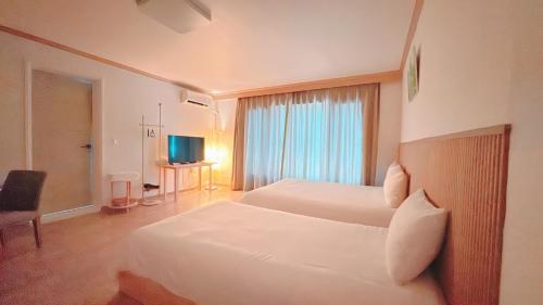a hotel room with two beds and a television at Garden in Jeju 201 in Seogwipo