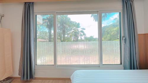 a bedroom with a window with a view of a balcony at Garden in Jeju 201 in Seogwipo