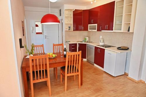 a kitchen with a wooden table and chairs and a kitchen with red cabinets at Villa Velestovo in Ohrid