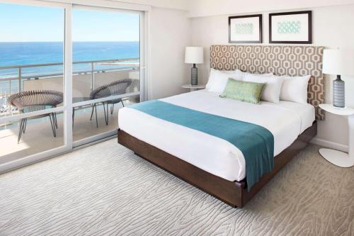 a bedroom with a large bed and a balcony at Ilikai Hotel & Luxury Suites in Honolulu