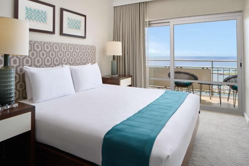 a hotel room with a bed and a balcony at Ilikai Hotel & Luxury Suites in Honolulu