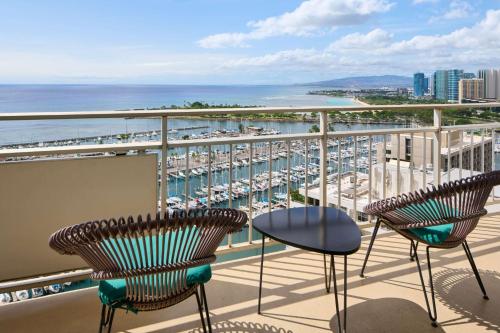 a balcony with chairs and a view of a harbor at Ilikai Hotel & Luxury Suites in Honolulu