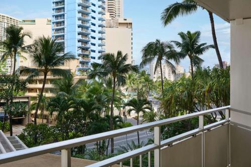 a balcony with palm trees and buildings at Ilikai Hotel & Luxury Suites in Honolulu