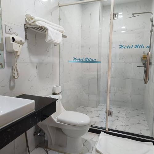 a white bathroom with a toilet and a shower at Hotel Totara in Dar es Salaam