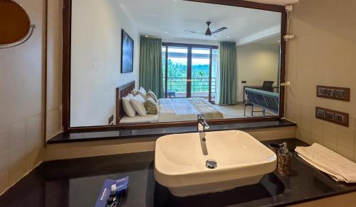 a bathroom with a sink and a large mirror at Pranavam Resort & Spa in Tariyod
