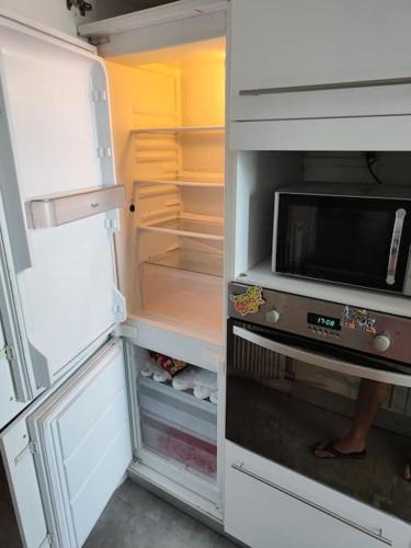 Elle comprend un réfrigérateur avec une porte ouverte et un four micro-ondes. dans l'établissement Appart 3 chambres 5 min centre, à Montpellier