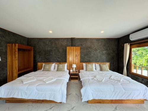 a bedroom with two beds and a window at Libong Loft Home in Ko Libong