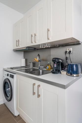 une cuisine avec un évier et une machine à laver dans l'établissement Apart Merryland Paris Châtelet, à Paris